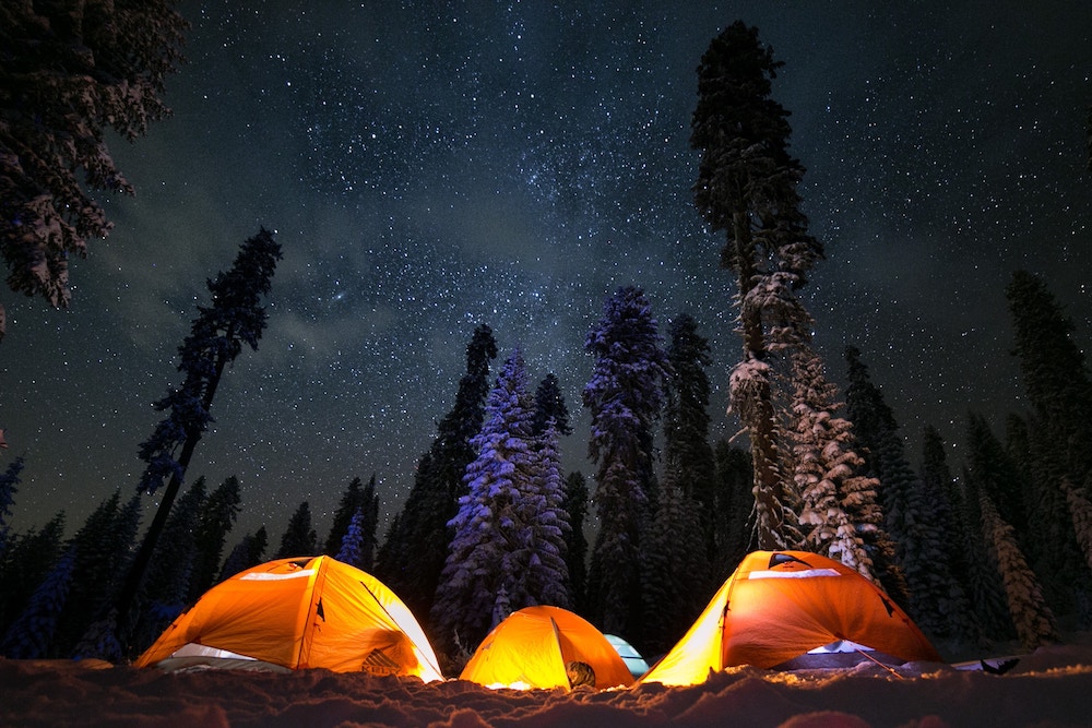 夜空の下テントをはってキャンプをする様子